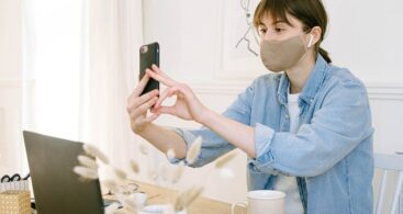 Lady wears a face mask and holds her mobile phone to her face