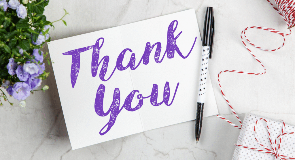 A thank you note and card with a pen on a desk