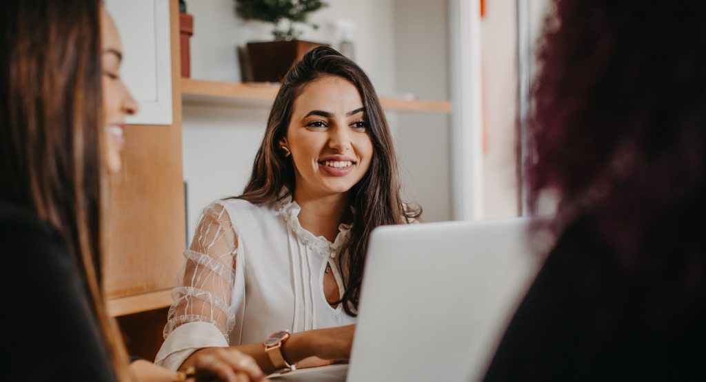 A business owner sits at a laptop with customers